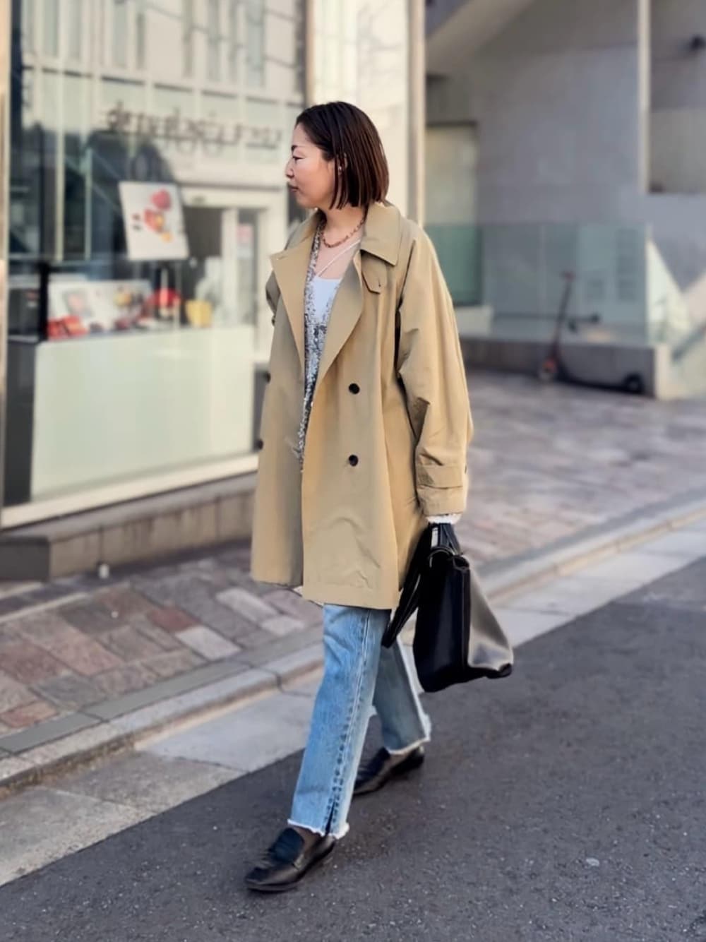 ベージュ系のトレンチコート、ブルー系のデニムパンツ、ブラック系のローファーを着用したレディースの冬コーディネートの1枚目の写真