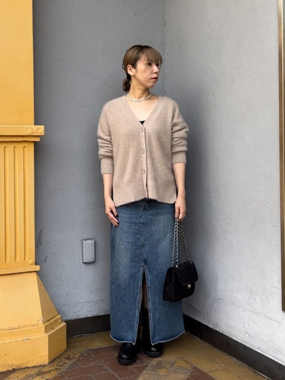 グレー系のカーディガン/ボレロ、ブルー系のデニムスカート、ブラック系のショルダーバッグを着用したレディースの冬コーディネートの1枚目の写真