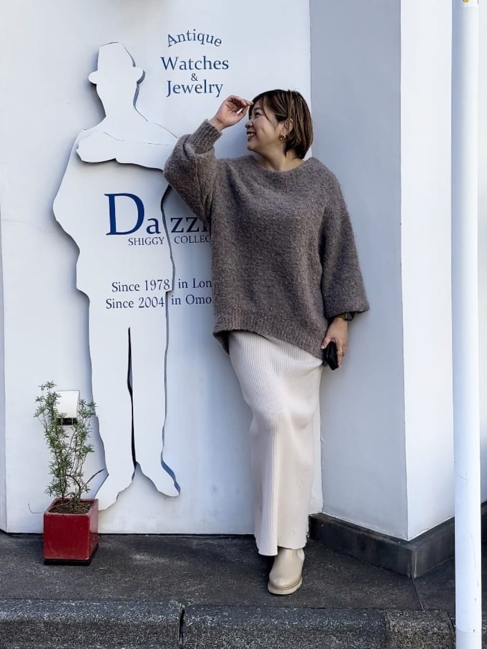 ベージュ系のスカート、ベージュ系のブーツ、ブラウン系のニット/セーターを着用したレディースの秋コーディネートの1枚目の写真