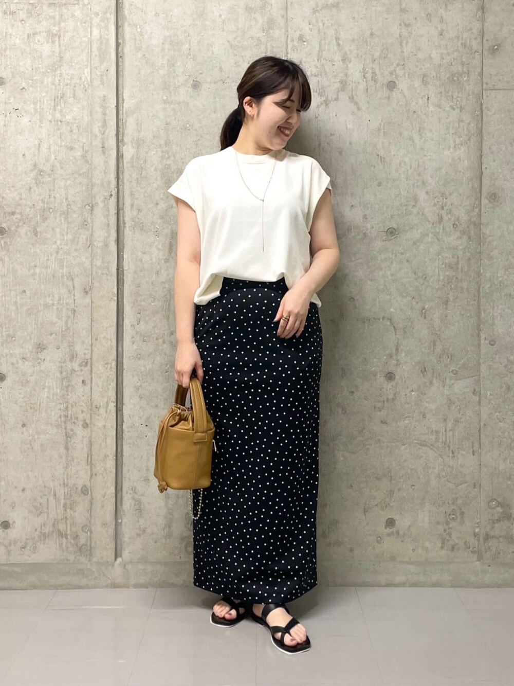 ホワイト系のニット/セーター、ブラック系のスカート、イエロー系のハンドバッグを着用したレディースの夏コーディネートの1枚目の写真