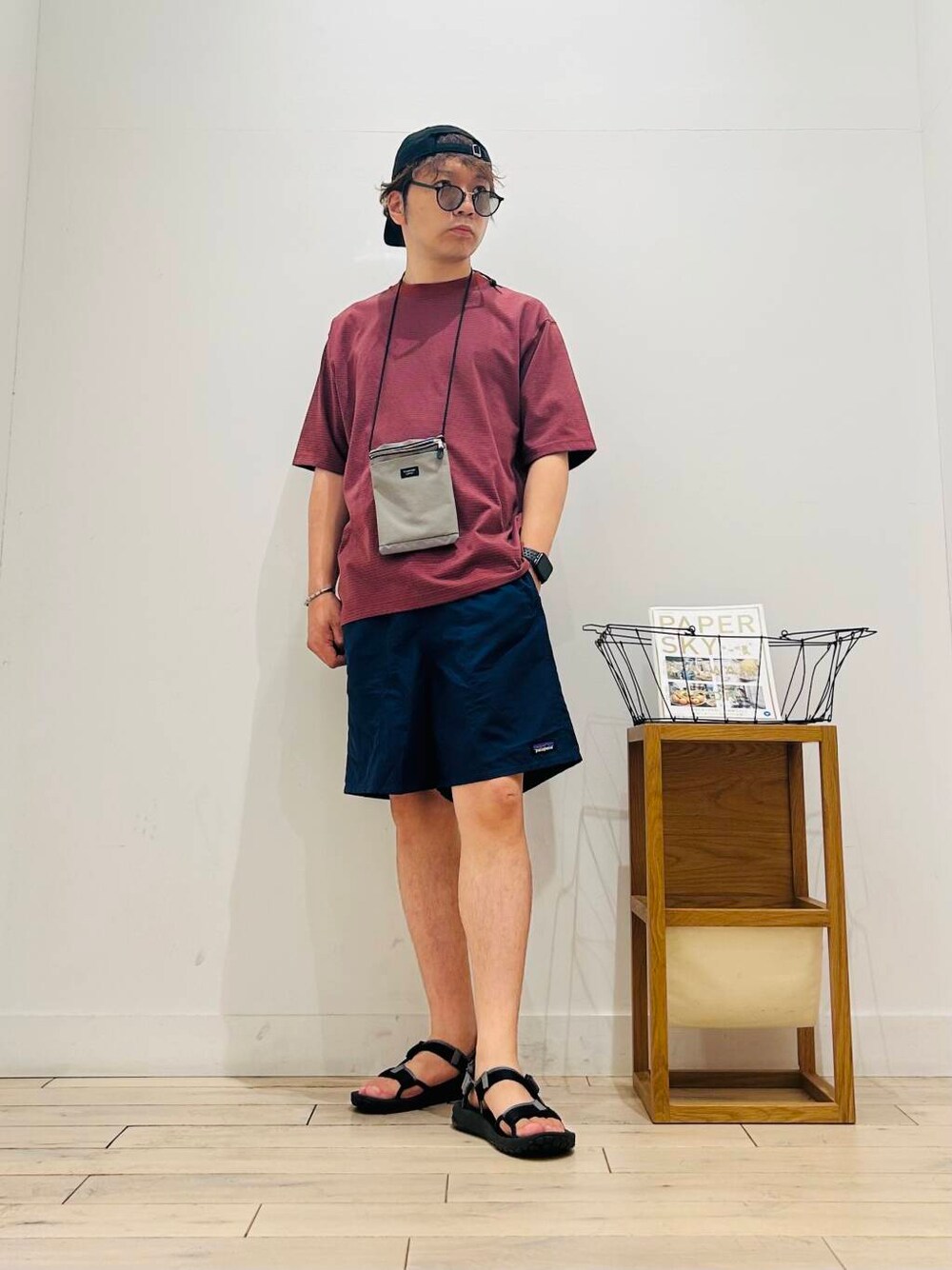 グレー系のショルダーバッグ、ブラック系のサンダル、オレンジ系のTシャツ/カットソーを着用したメンズの夏コーディネートの1枚目の写真