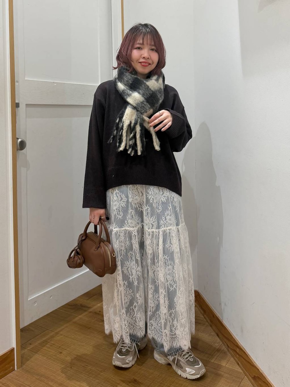 ブルー系のデニムパンツ、ブラウン系のワンピース、ブラウン系のハンドバッグを着用したレディースの秋コーディネートの1枚目の写真