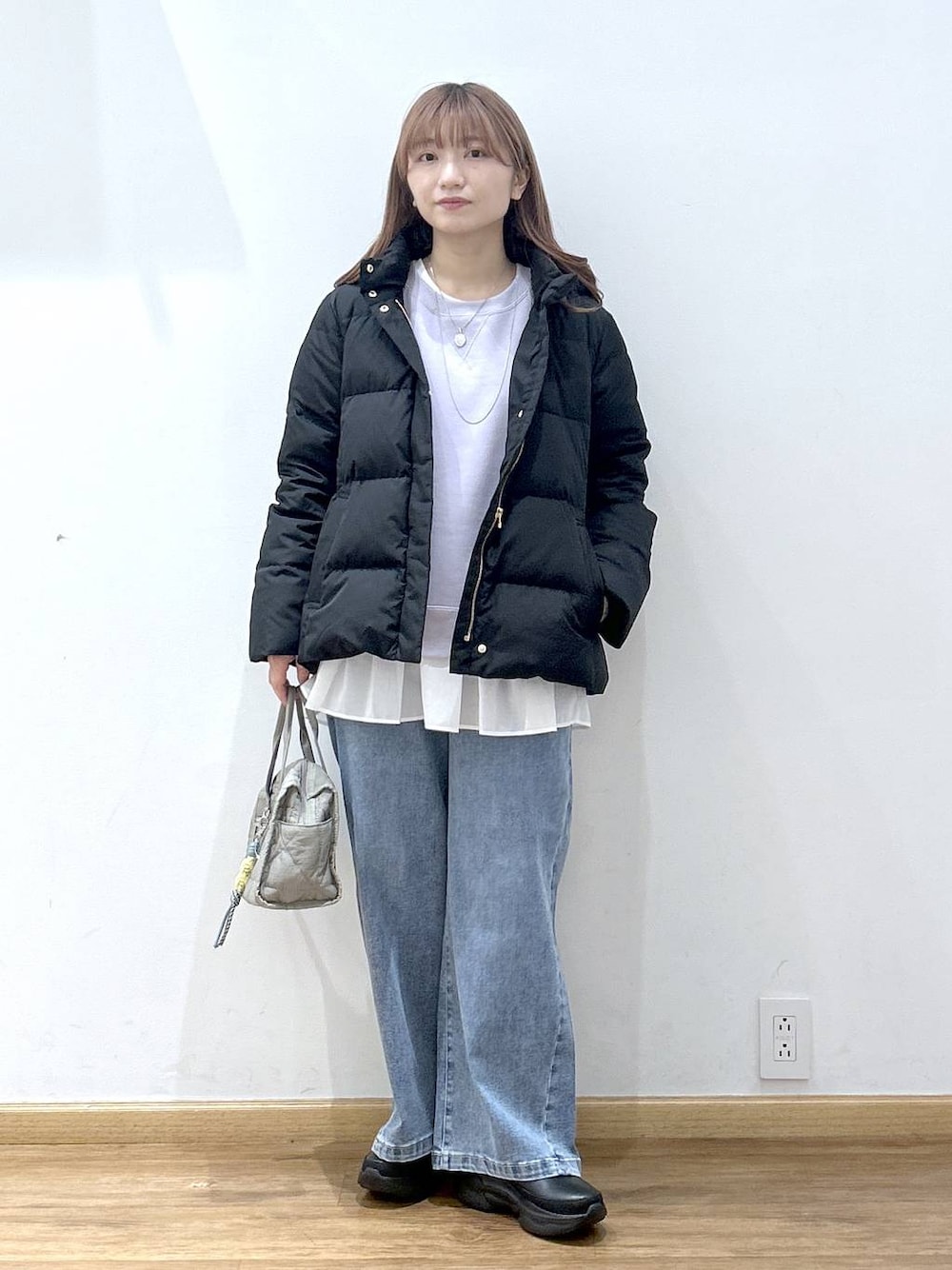 ブラック系のダウンジャケット/コート、グリーン系のボストンバッグ、ホワイト系のTシャツ/カットソーを着用したレディースの冬コーディネートの1枚目の写真