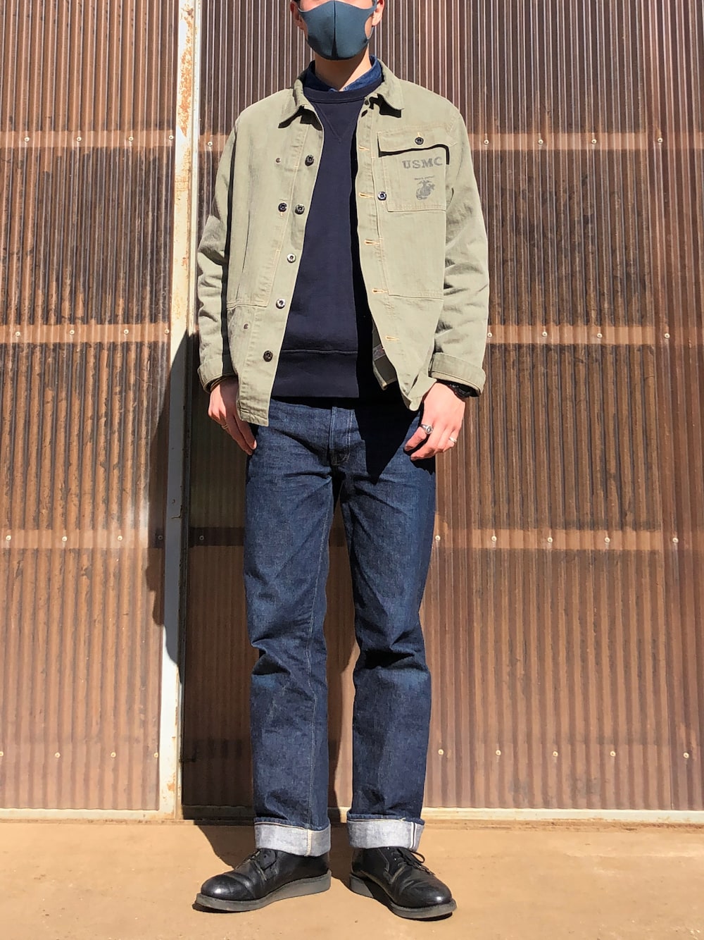 ブルー系のデニムパンツ、ブラック系のブーツ、グリーン系のミリタリージャケットを着用したメンズの冬コーディネートの1枚目の写真