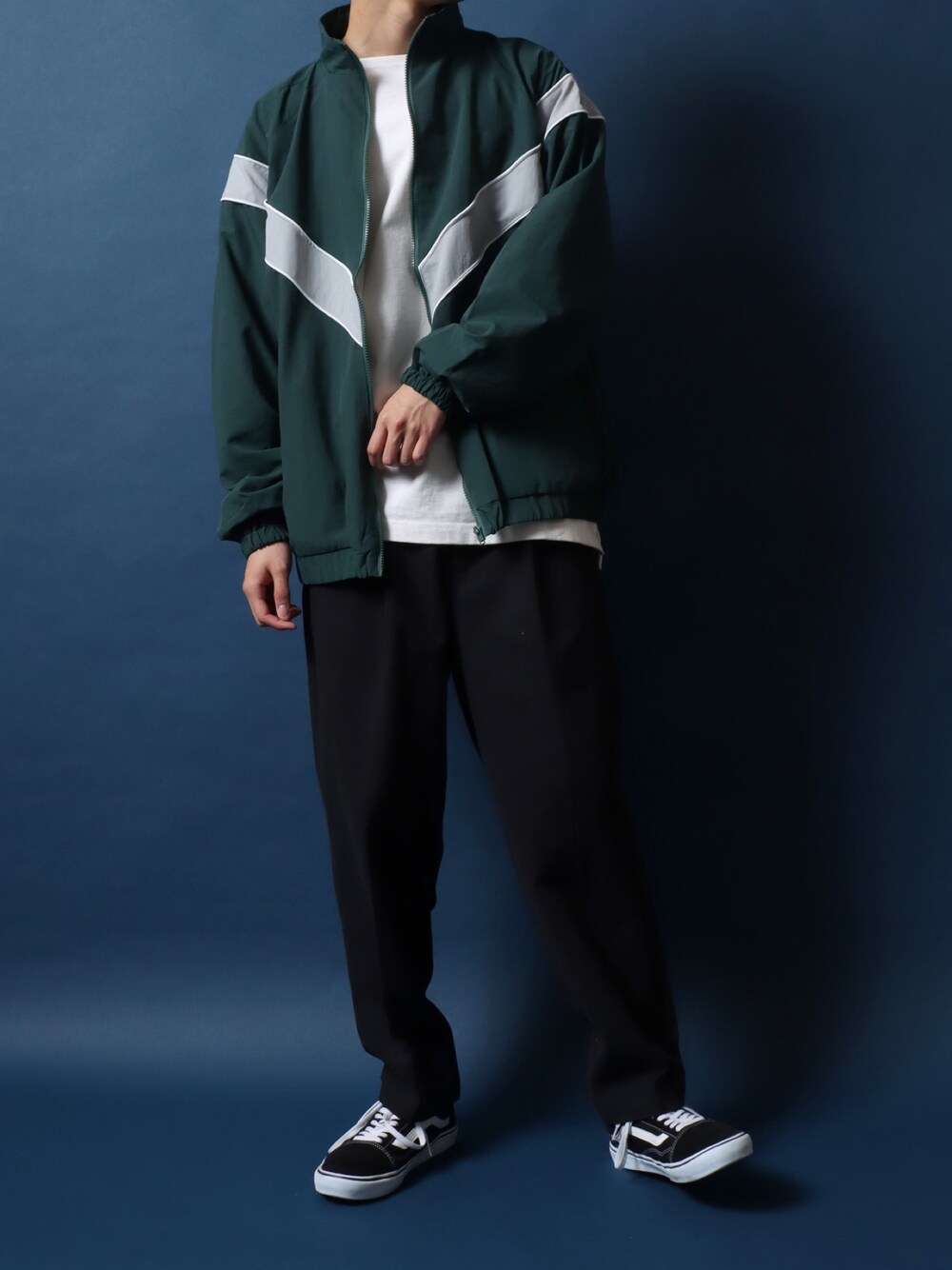 グリーン系のナイロンジャケット、ホワイト系のTシャツ/カットソー、ブラック系のチノパンツを着用したメンズの春コーディネートの1枚目の写真