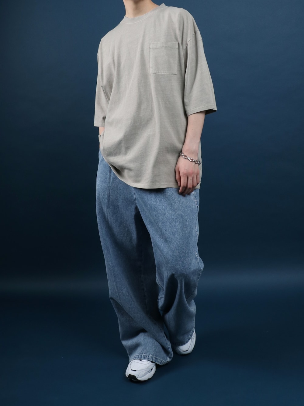 ブルー系のデニムパンツ、ホワイト系のスニーカー、ベージュ系のTシャツ/カットソーを着用したメンズの夏コーディネートの1枚目の写真