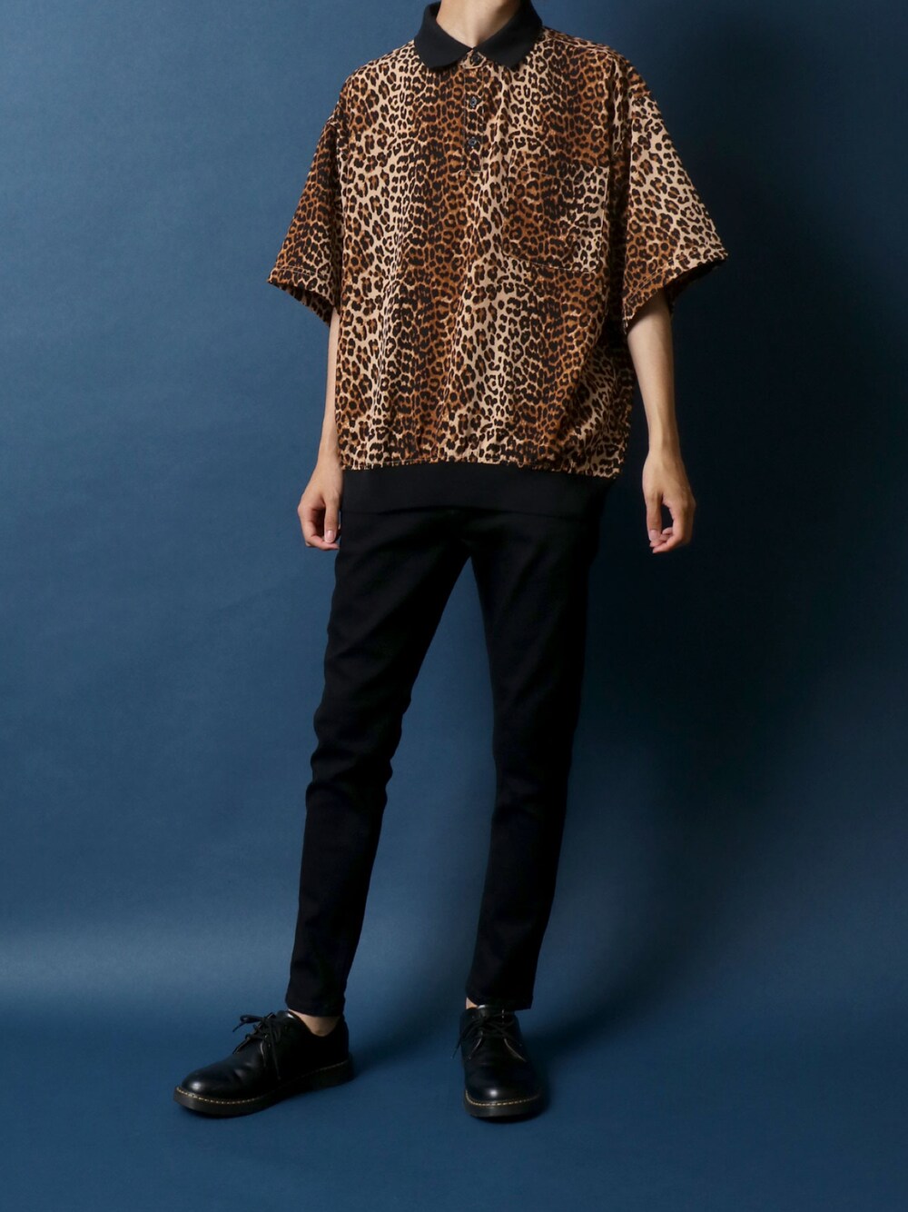 ブラウン系のポロシャツ、ブラック系のデニムパンツ、ブラック系のドレスシューズを着用したメンズの夏コーディネートの1枚目の写真