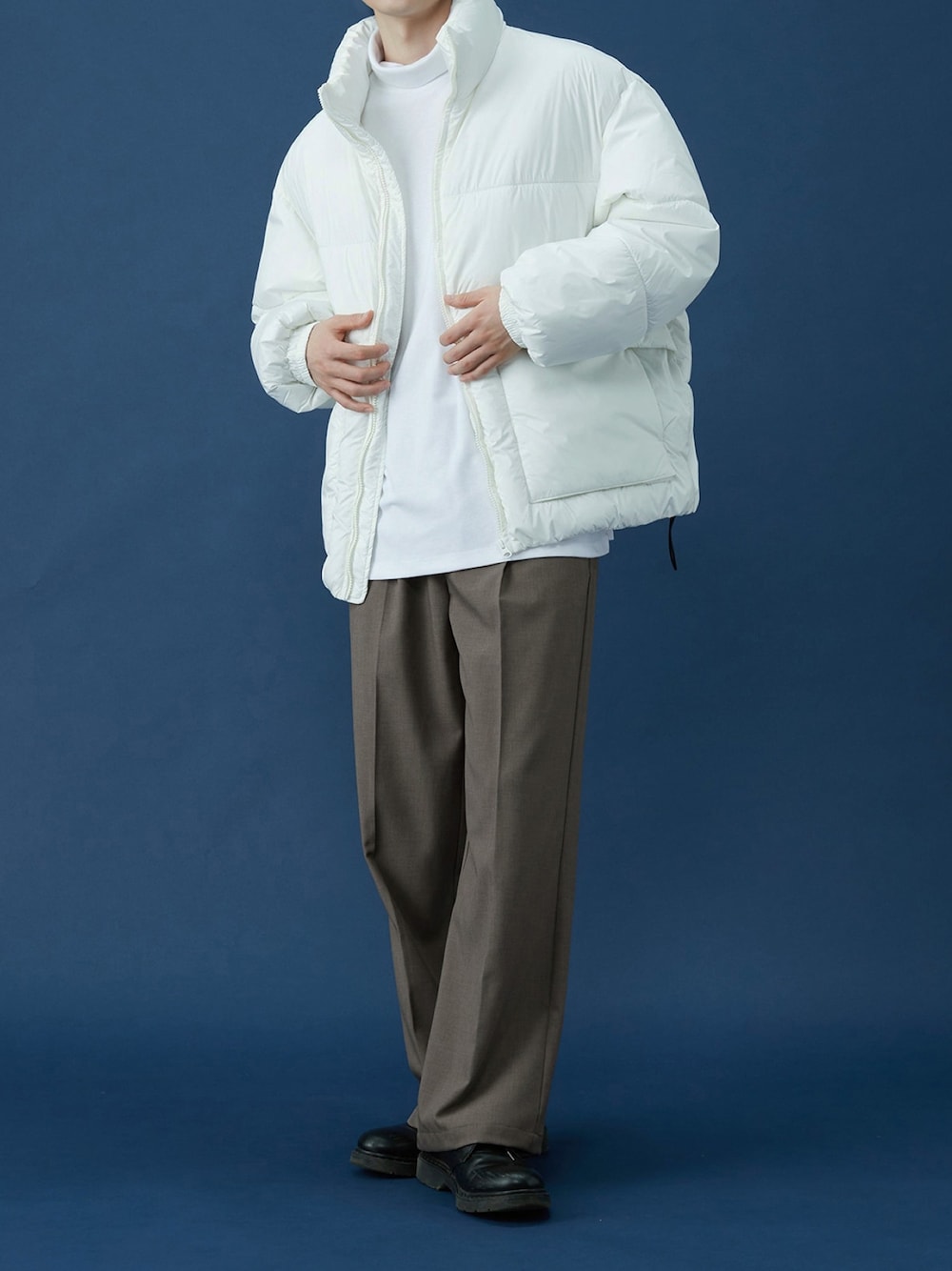 ブラウン系のスラックス、ホワイト系のダウンジャケット/コート、ブラック系のベルトを着用したメンズの冬コーディネートの1枚目の写真