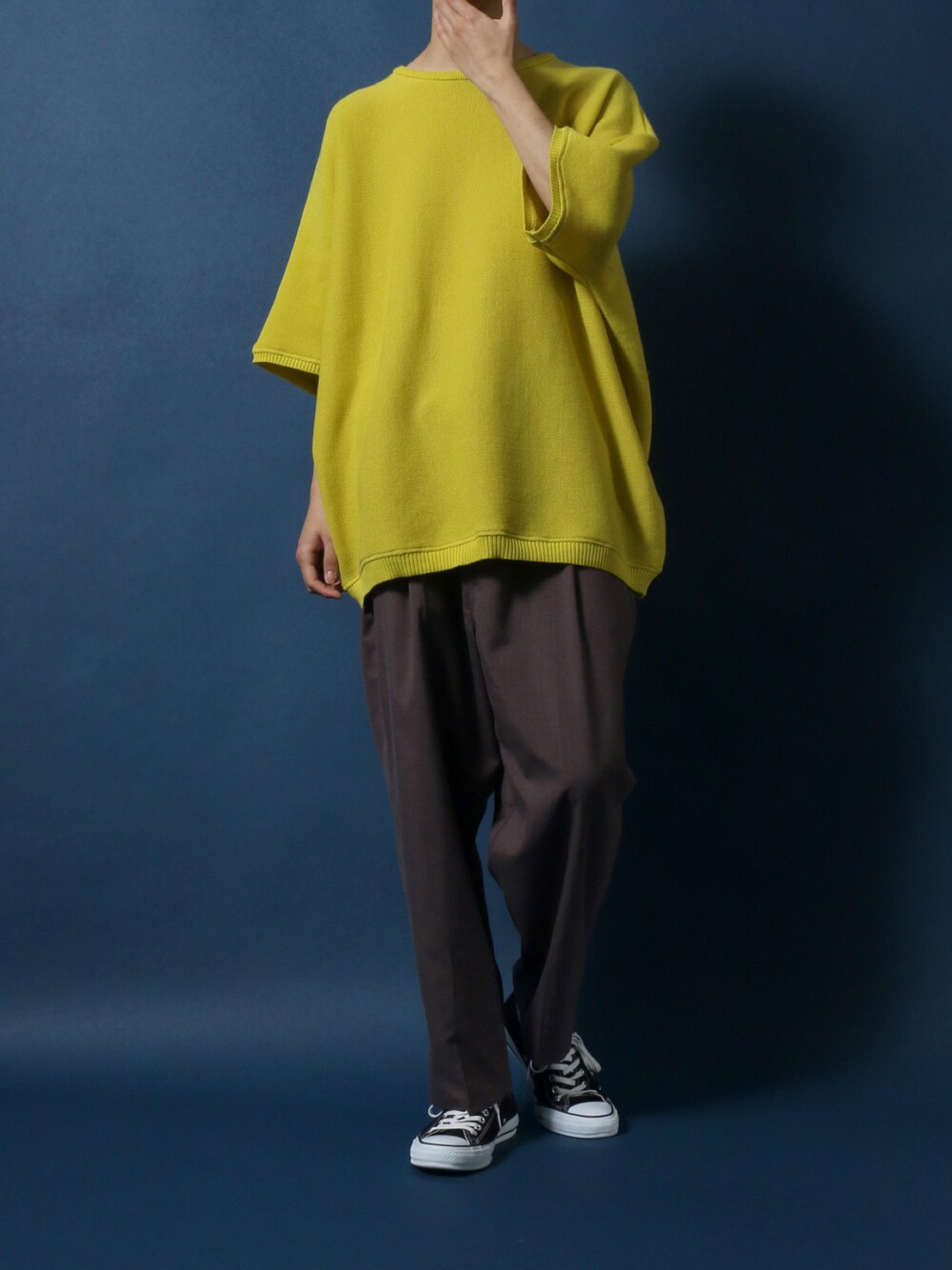 イエロー系のニット/セーター、ベージュ系のスラックス、ブラック系のスニーカーを着用したメンズの春コーディネートの1枚目の写真