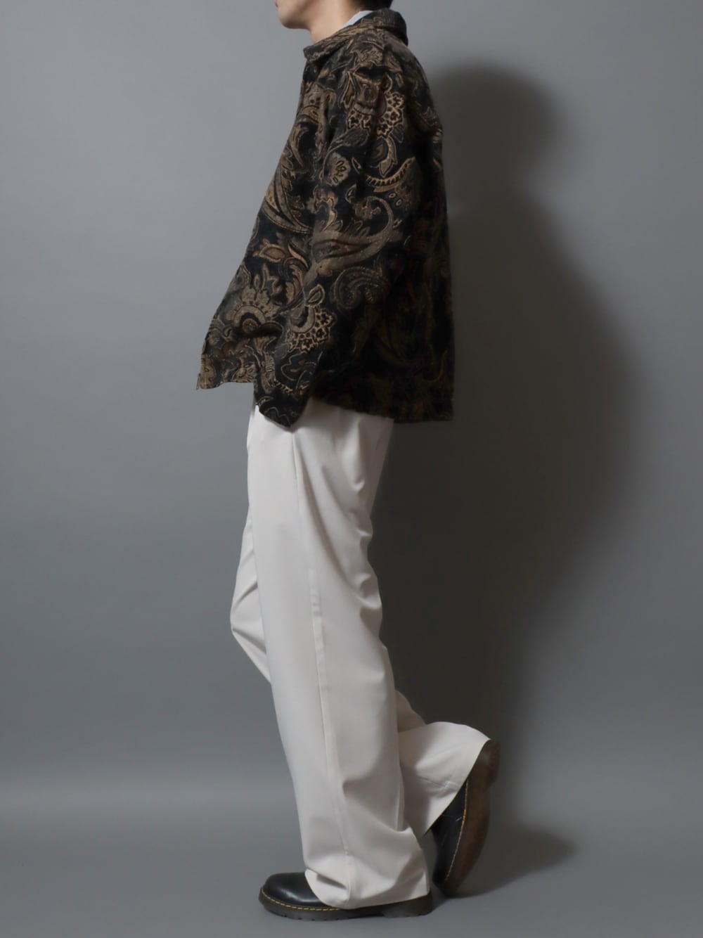 ブラック系のドレスシューズ、ホワイト系のスラックス、ブラック系のブルゾンを着用したメンズの春コーディネートの1枚目の写真