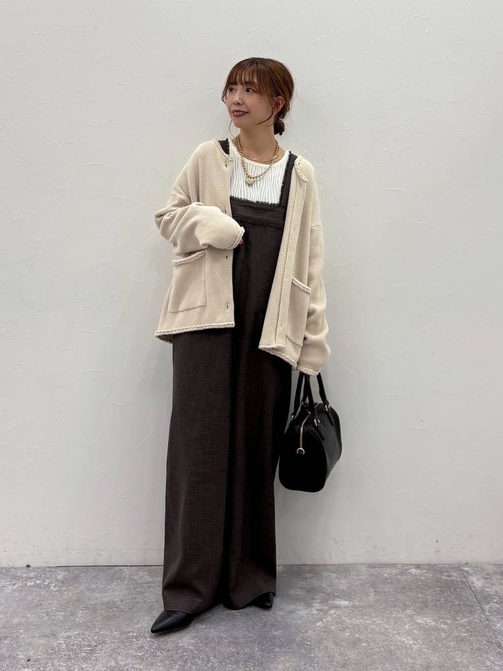 ベージュ系のTシャツ/カットソー、ベージュ系のカーディガン/ボレロ、ブラック系のボストンバッグを着用したレディースの冬コーディネートの1枚目の写真