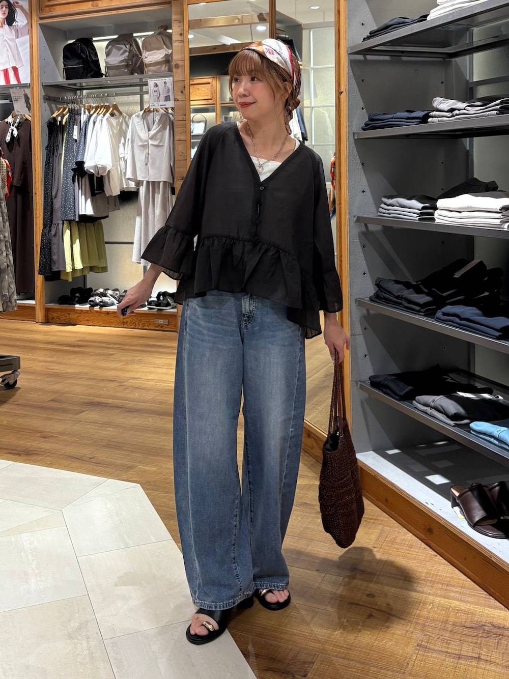 ブルー系のデニムパンツ、ホワイト系のタンクトップ、ブラウン系のクラッチバッグを着用したレディースの夏コーディネートの1枚目の写真