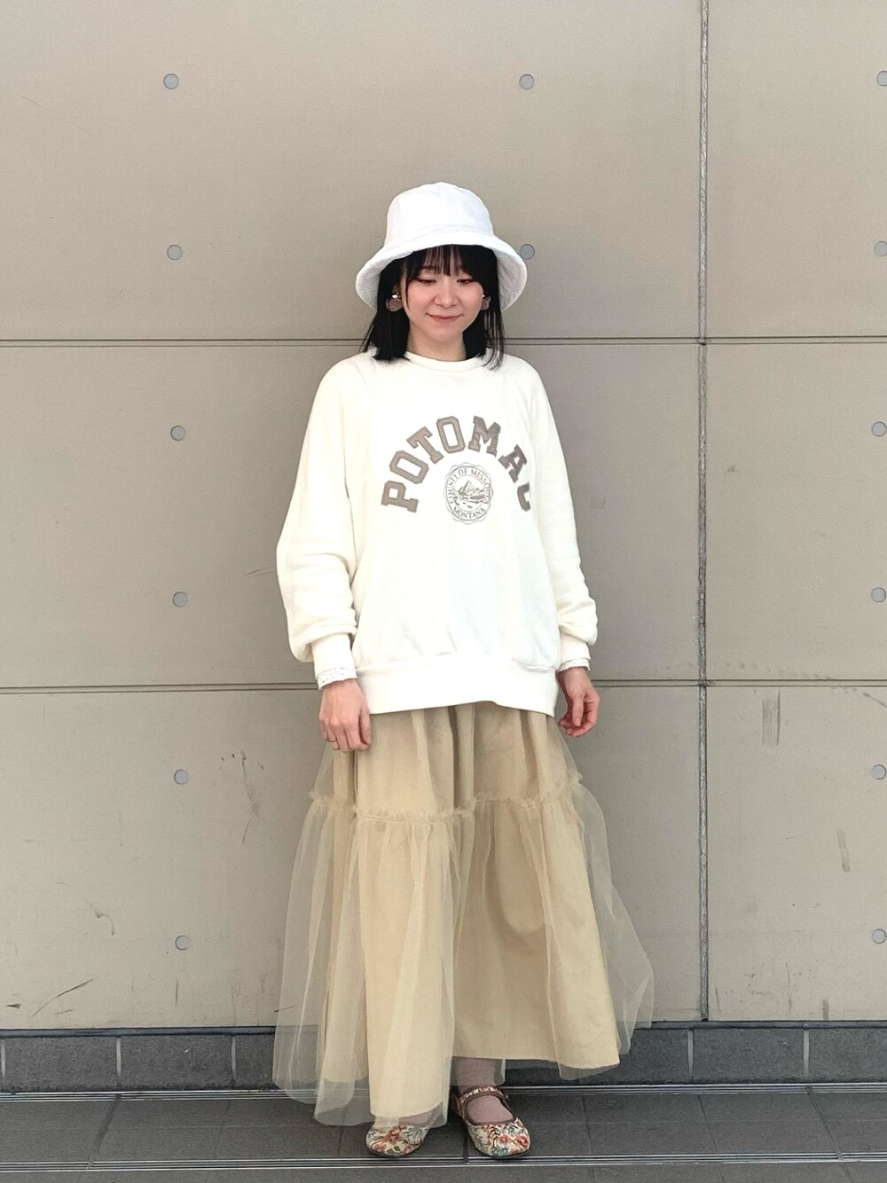 ホワイト系のスウェット、ベージュ系のスカート、ベージュ系のドレスシューズを着用したレディースの冬コーディネートの1枚目の写真