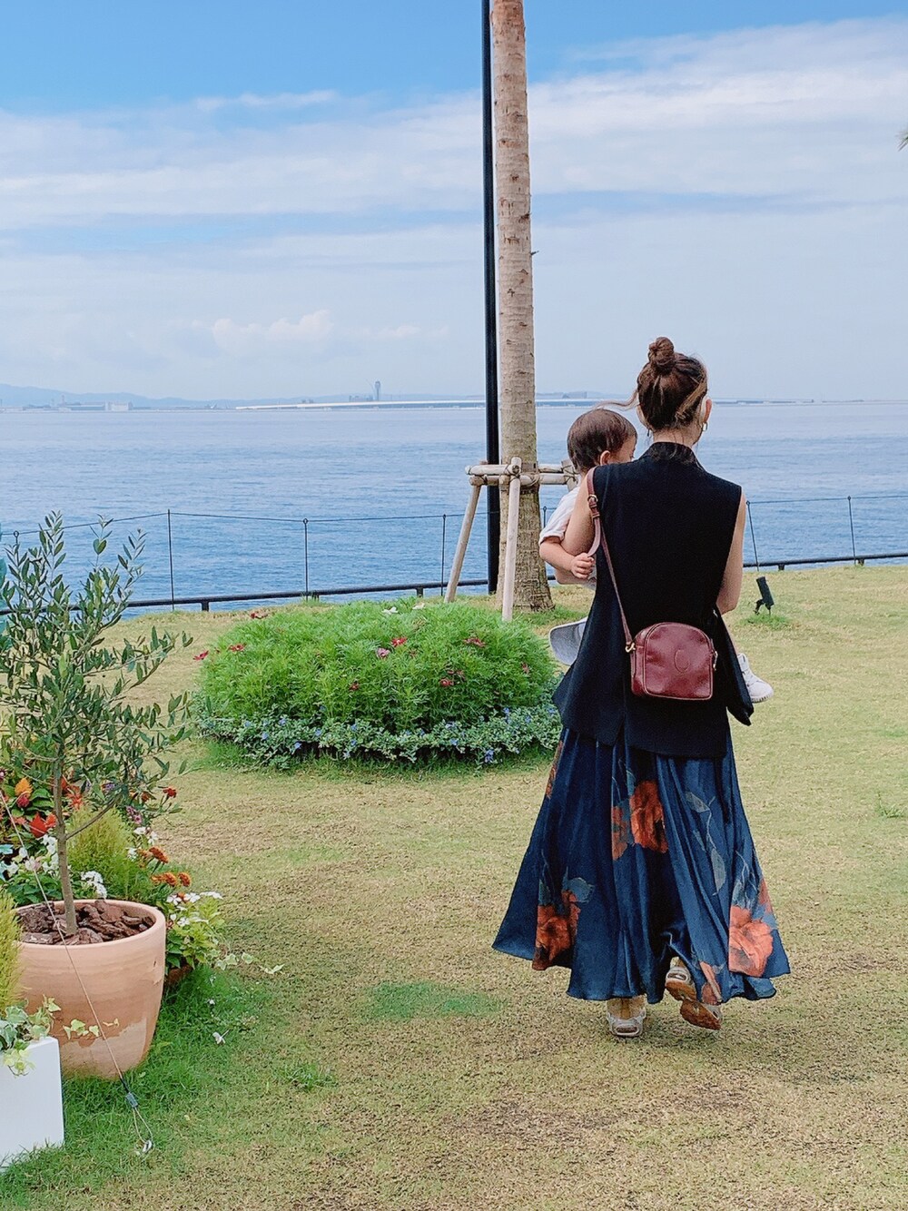 ブラウン系のショルダーバッグ、ブルー系のスカート、ブラック系のテーラードジャケットを着用したレディースの秋コーディネートの1枚目の写真