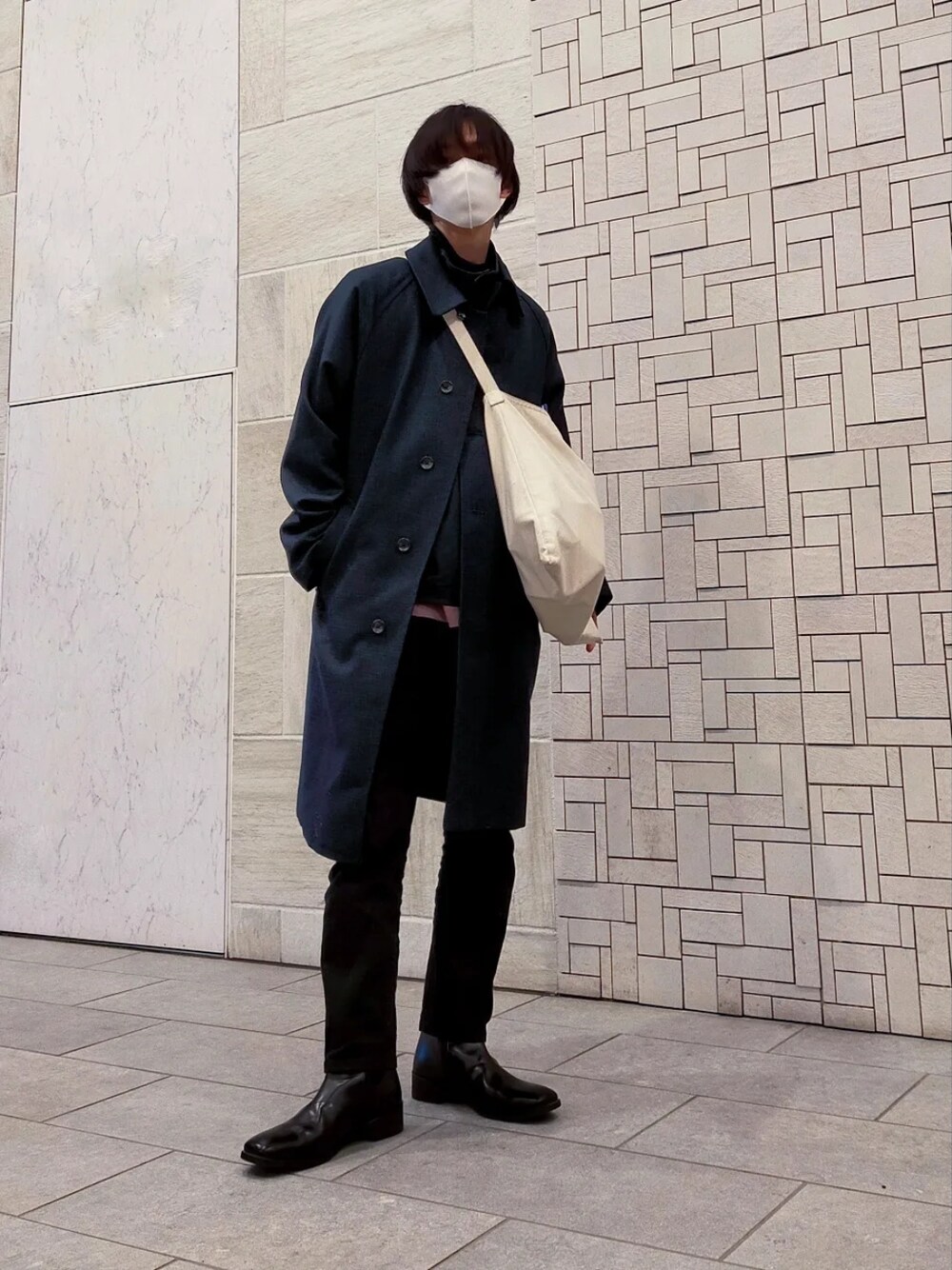 ブルー系のチェスターコート、ブラック系のパンツ、ピンク系のスウェットを着用したメンズの冬コーディネートの1枚目の写真