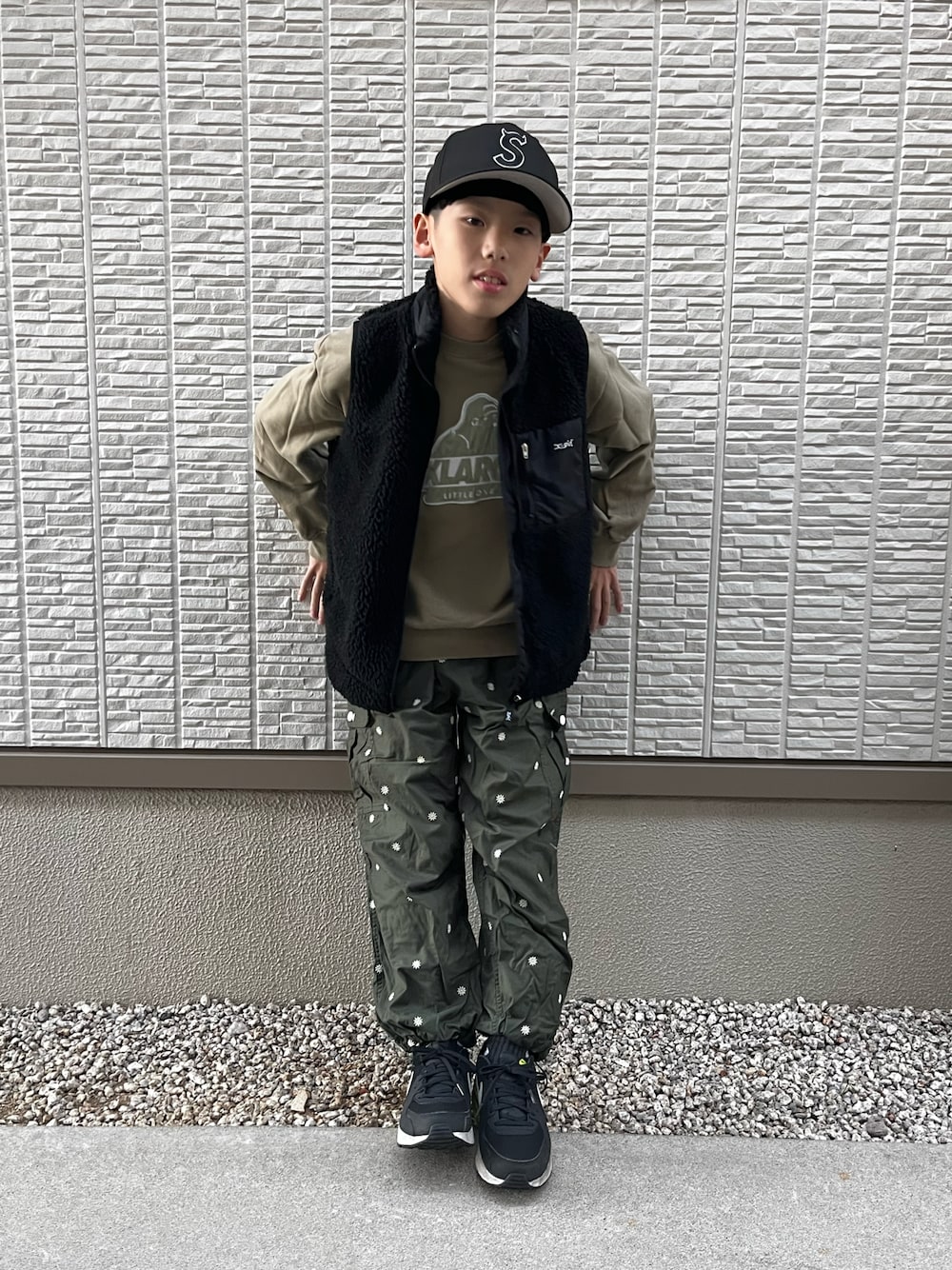 グリーン系のスウェット、ブラック系のベスト、グリーン系のカーゴパンツを着用したレディースの冬コーディネートの1枚目の写真