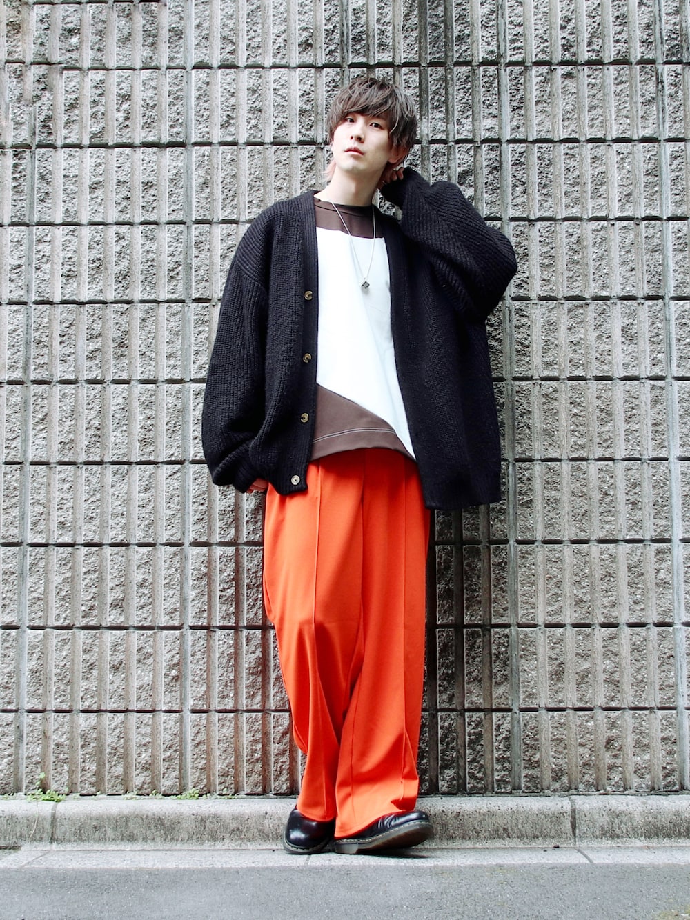 ブラウン系のTシャツ/カットソー、ブラック系のカーディガン/ボレロ、オレンジ系のパンツを着用したメンズの春コーディネートの1枚目の写真