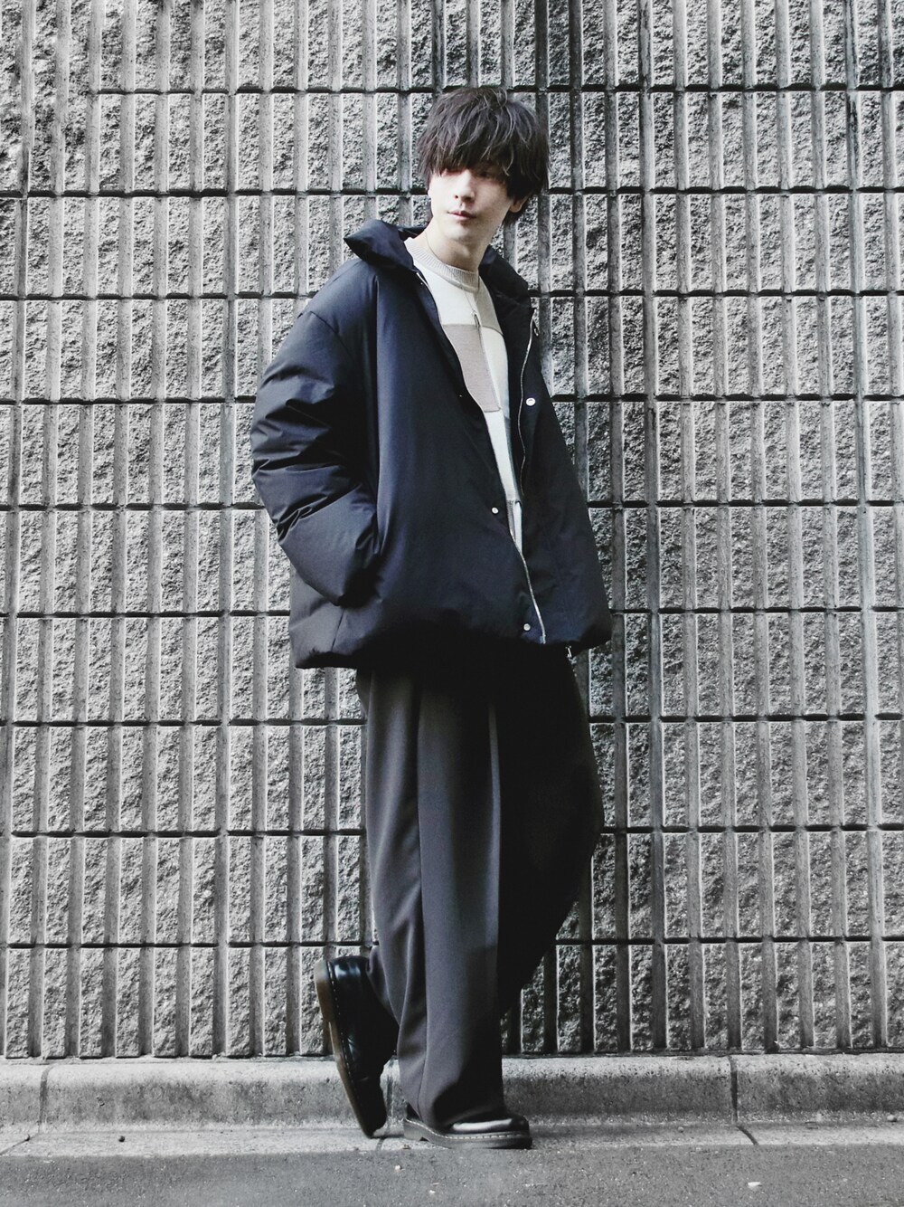 ブラック系のダウンジャケット/コート、ベージュ系のニット/セーター、グレー系のスラックスを着用したメンズの秋コーディネートの1枚目の写真