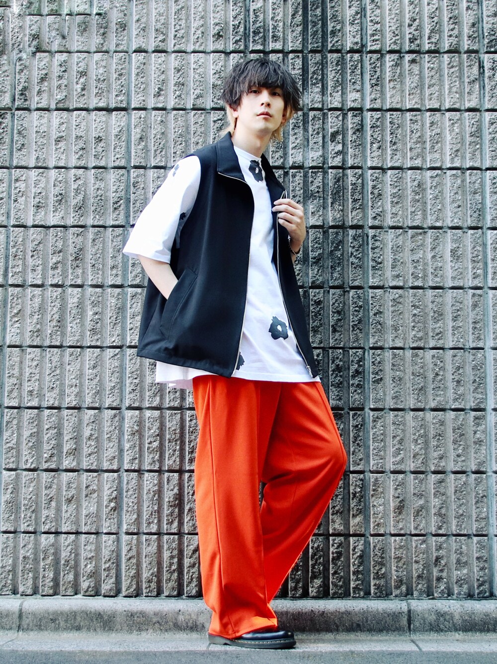 ブラック系のベスト、ホワイト系のTシャツ/カットソー、オレンジ系のパンツを着用したメンズの春コーディネートの1枚目の写真