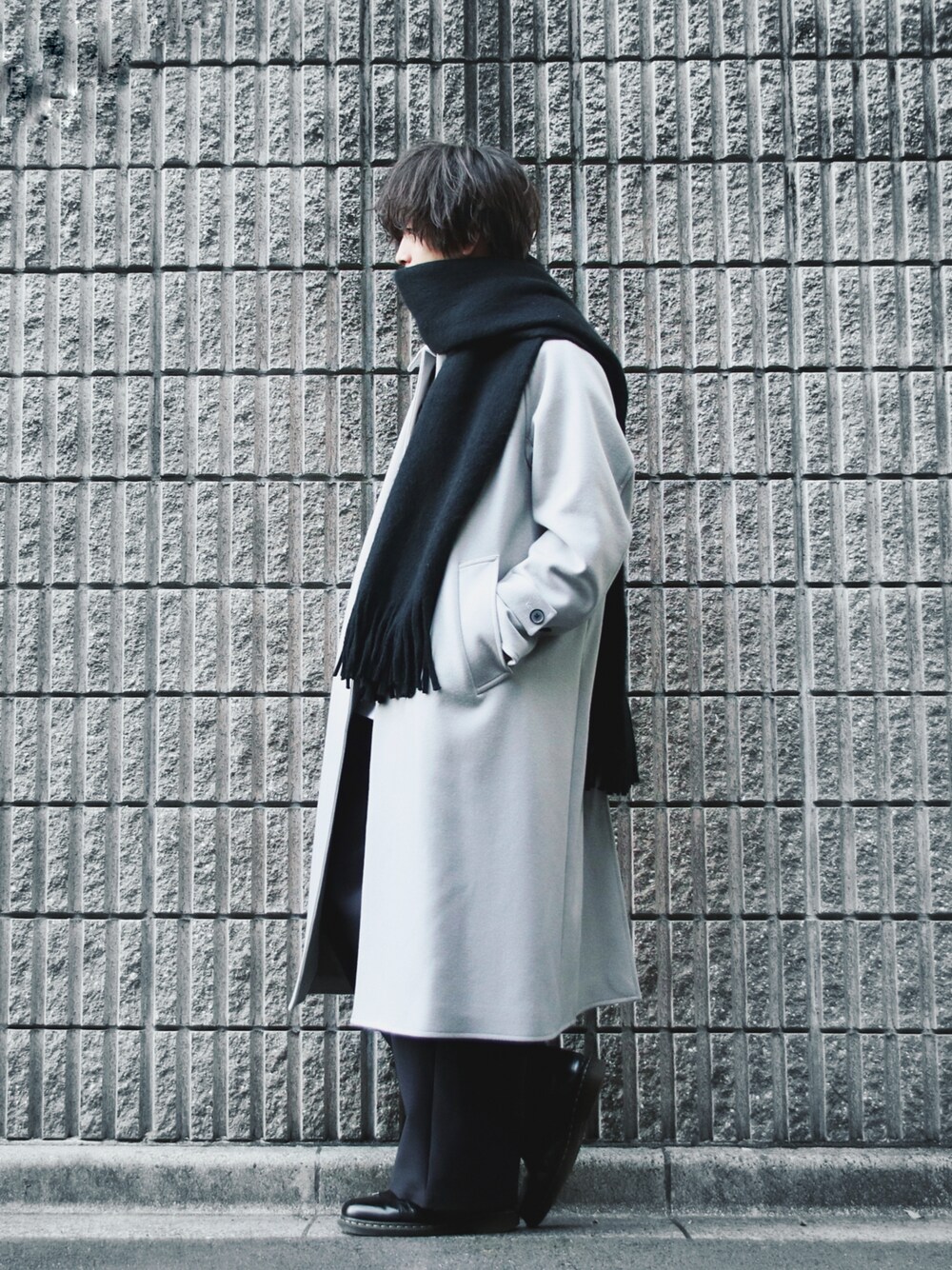 グレー系のステンカラーコート、グレー系のスラックス、ブラック系のドレスシューズを着用したメンズの冬コーディネートの1枚目の写真