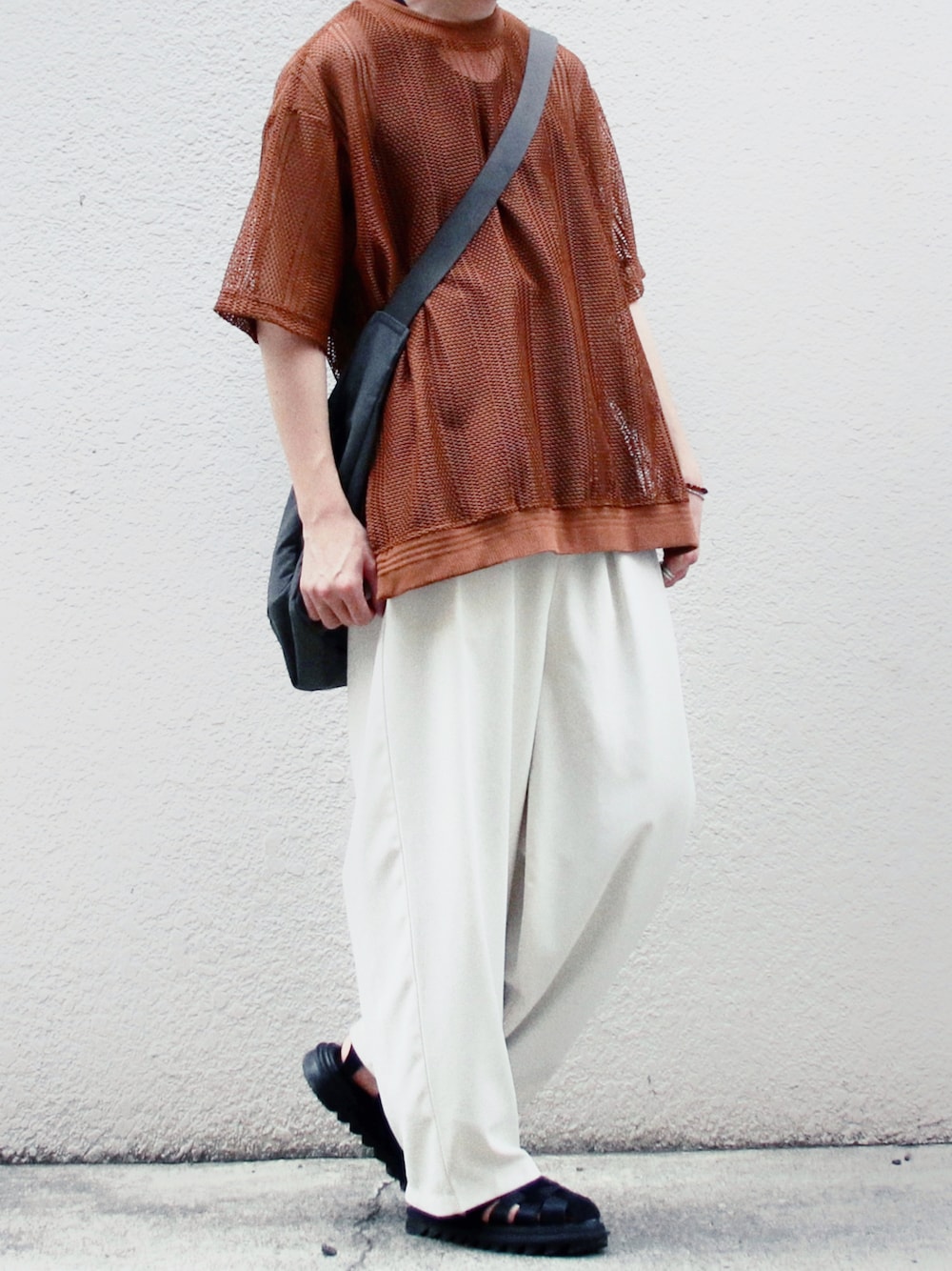 ブラウン系のTシャツ/カットソー、ベージュ系のスラックス、ブラック系のサンダルを着用したメンズの夏コーディネートの1枚目の写真