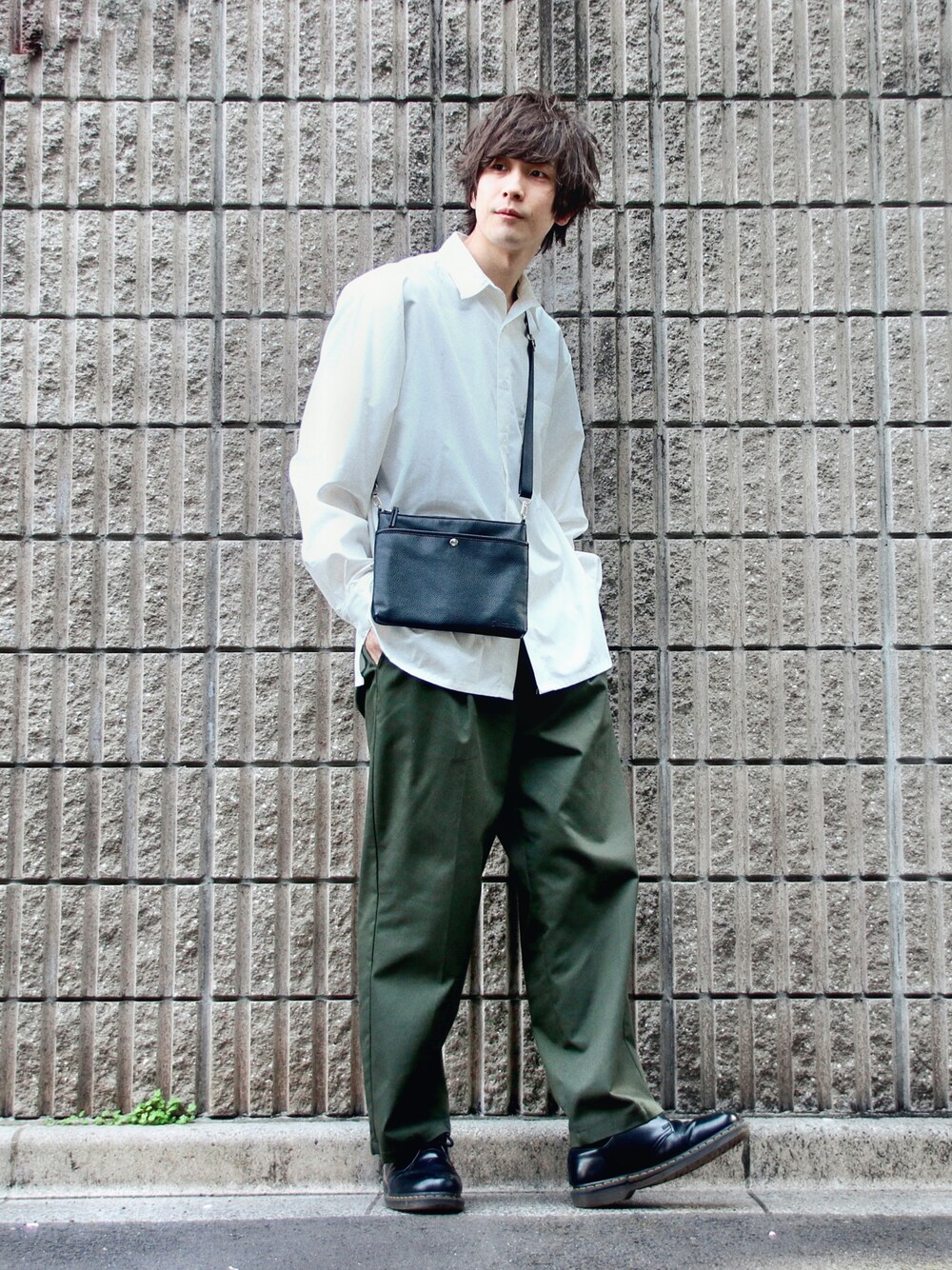 グリーン系のチノパンツ、ブラック系のショルダーバッグ、ホワイト系のシャツ/ブラウスを着用したメンズの春コーディネートの1枚目の写真
