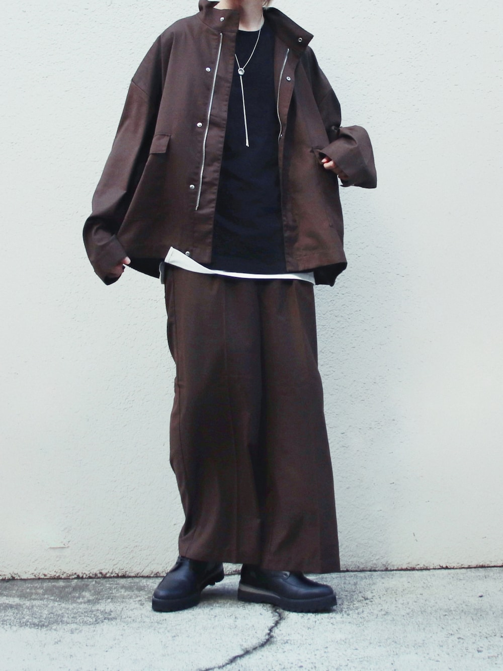 ブラウン系のブルゾン、ホワイト系のタンクトップ、ブラック系のドレスシューズを着用したメンズの夏コーディネートの1枚目の写真