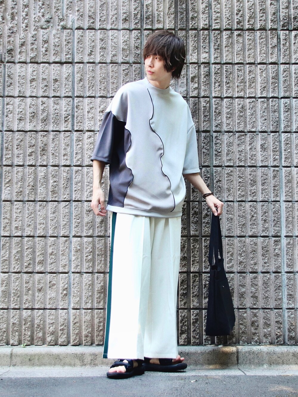 ホワイト系のスラックス、ブラック系のサンダル、ブラック系のトートバッグを着用したメンズの夏コーディネートの1枚目の写真