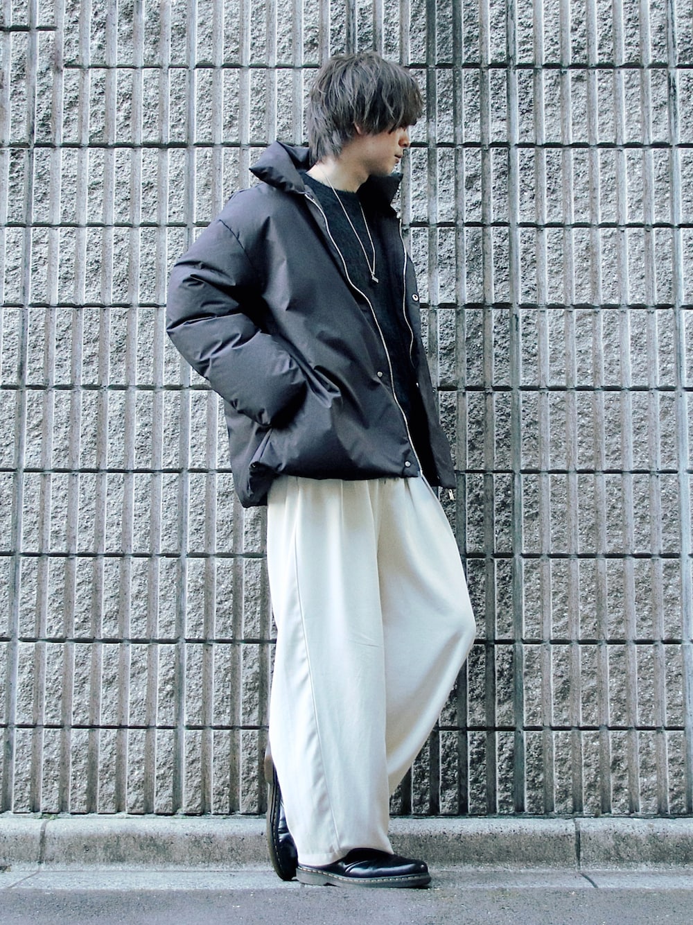 ブラック系のダウンジャケット/コート、ブラック系のニット/セーター、ベージュ系のスラックスを着用したメンズの冬コーディネートの1枚目の写真