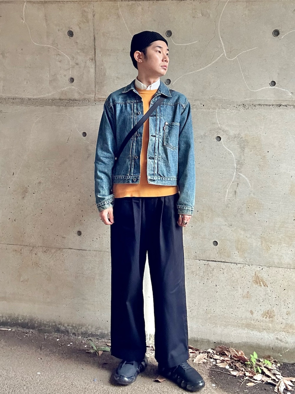 ブルー系のデニムジャケット、ホワイト系のショルダーバッグ、イエロー系のニット/セーターを着用したメンズの春コーディネートの1枚目の写真