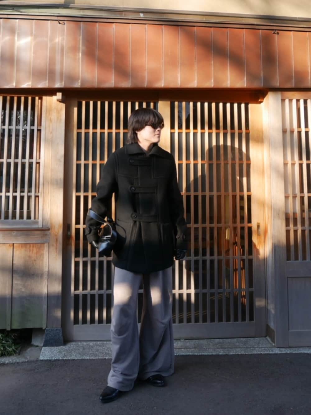 ブラック系のダッフルコート、グレー系のスウェットパンツ、ブラック系のドレスシューズを着用したメンズの春コーディネートの1枚目の写真