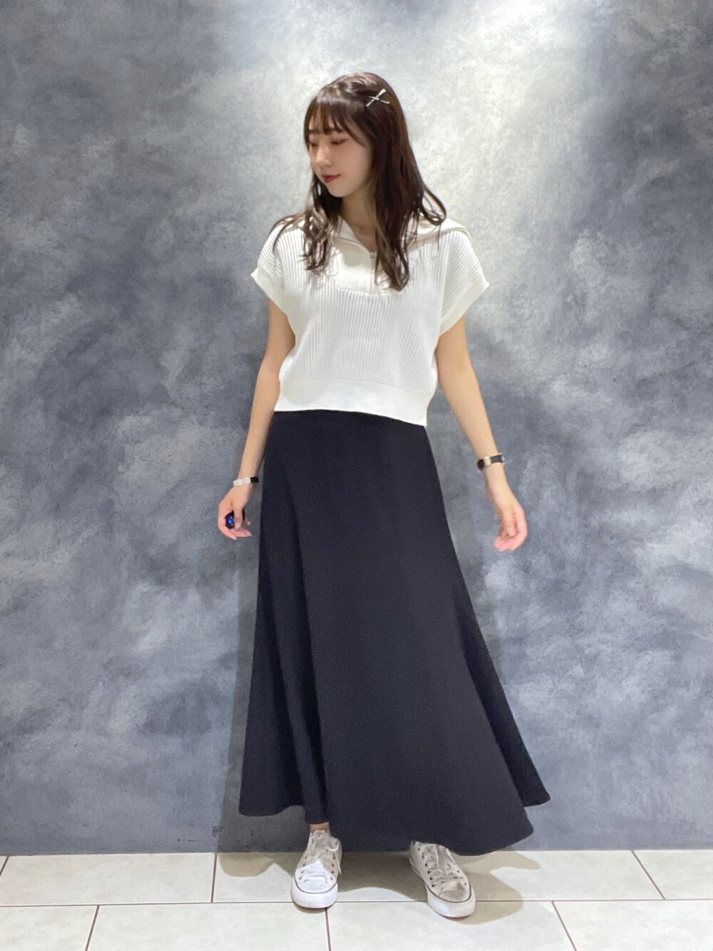 ホワイト系のニット/セーター、ブラック系のスカート、ホワイト系のスニーカーを着用したレディースの夏コーディネートの1枚目の写真