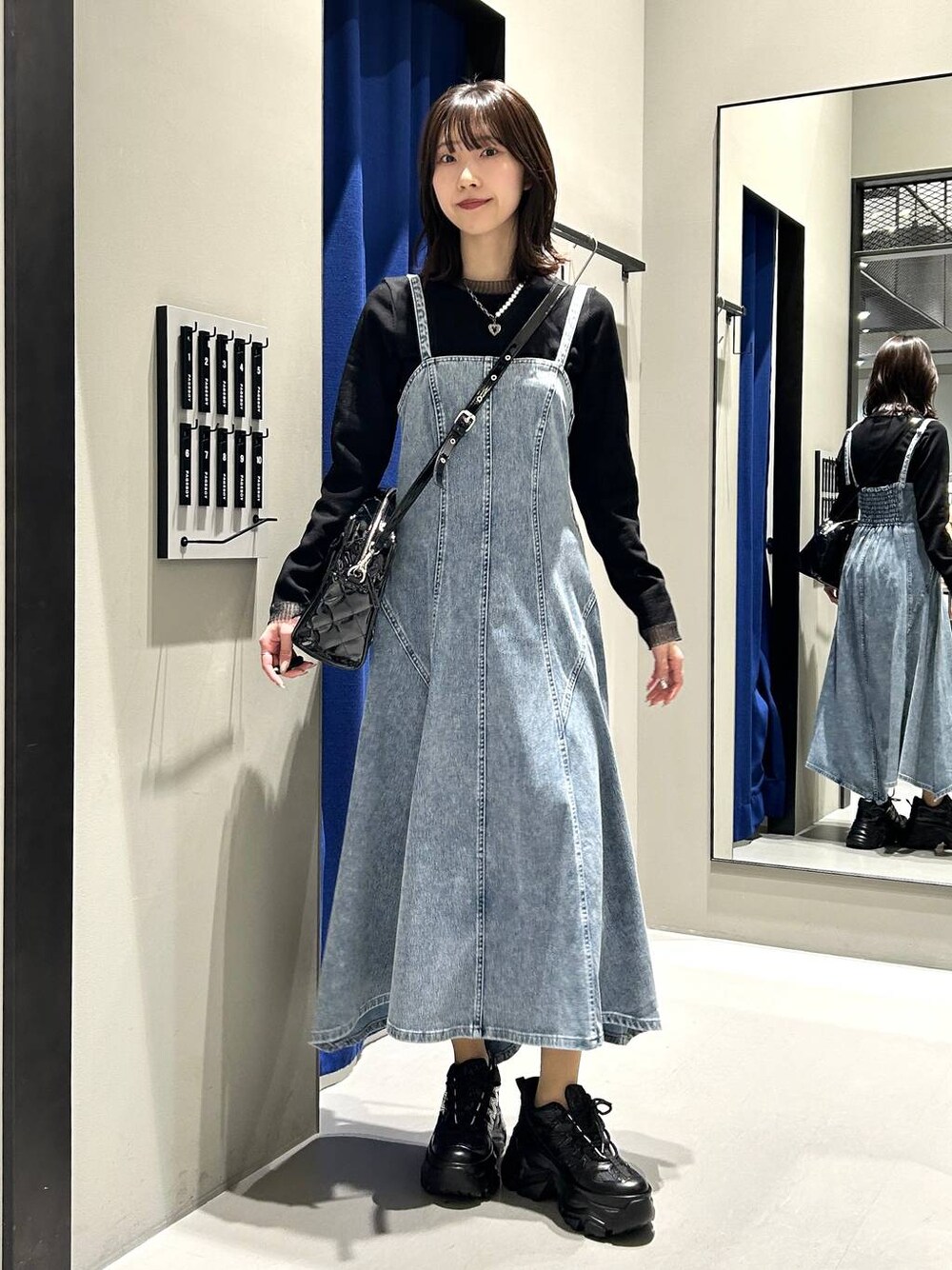 ブラック系のスニーカー、ブラック系のボストンバッグ、ブラック系のニット/セーターを着用したレディースの冬コーディネートの1枚目の写真