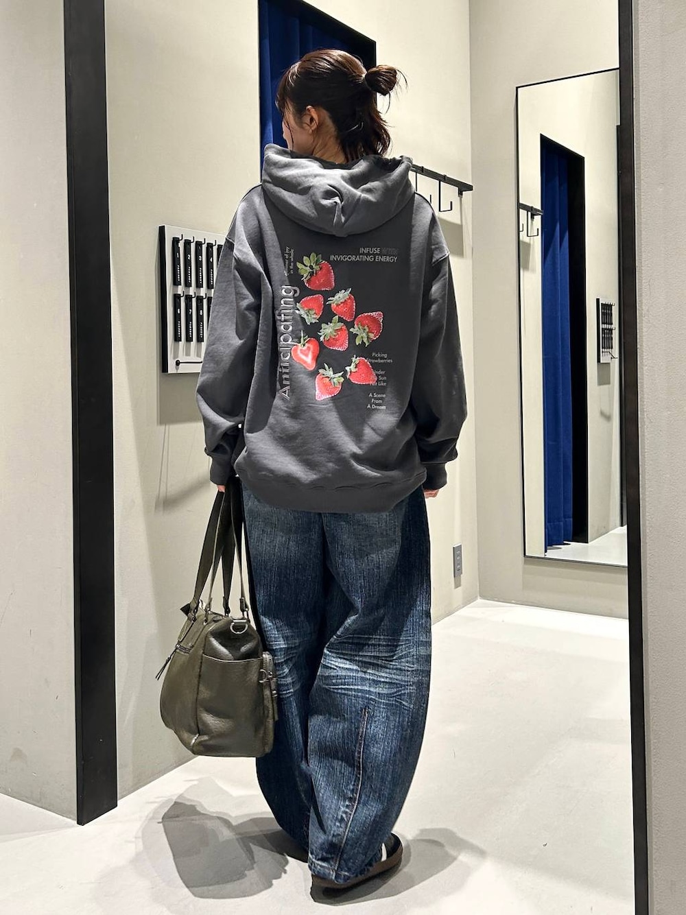 グリーン系のボストンバッグ、グレー系のパーカー、ブルー系のデニムパンツを着用したレディースの秋コーディネートの1枚目の写真