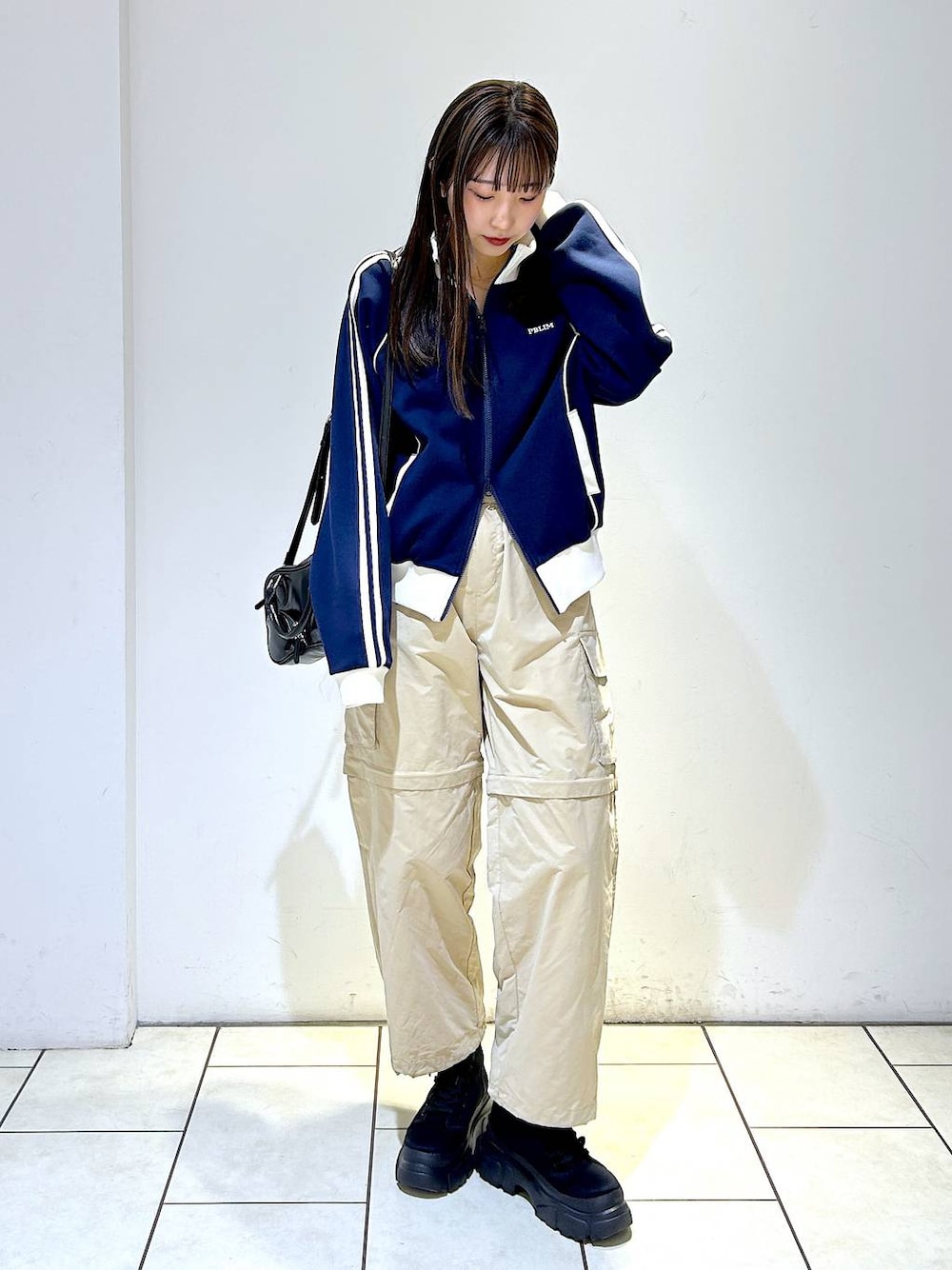 ブルー系のセットアップ、ブラック系のボストンバッグ、ブラック系のブーツを着用したレディースの冬コーディネートの1枚目の写真