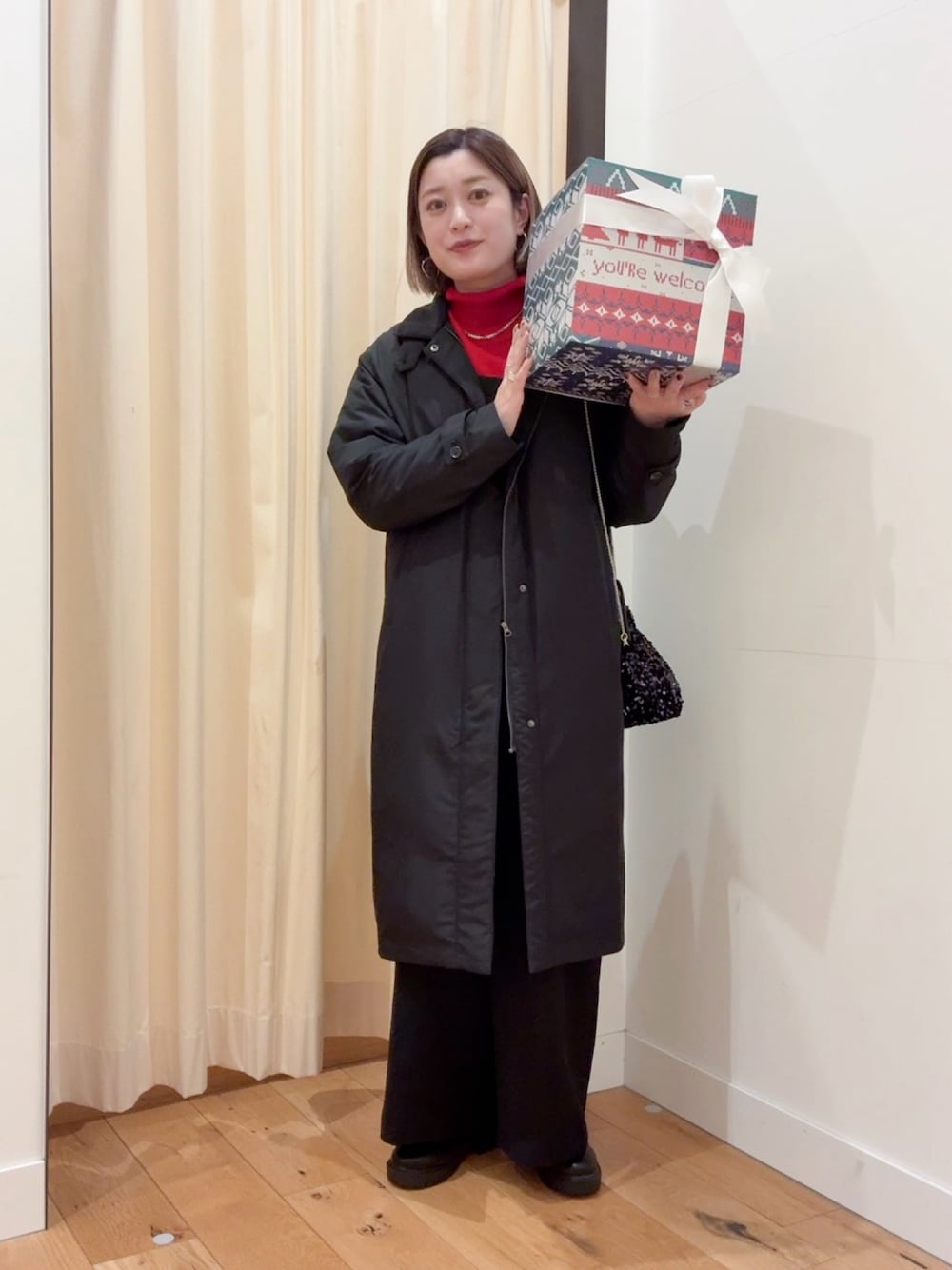 レッド系のニット/セーター、ブラック系のダウンジャケット/コート、ブラック系のサロペット/オーバーオールを着用したレディースの秋コーディネートの1枚目の写真