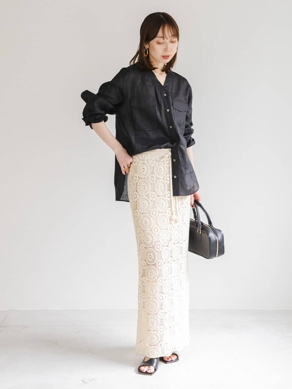 ブラック系のシャツ/ブラウス、ホワイト系のスカート、ブラック系のショルダーバッグを着用したレディースの夏コーディネートの1枚目の写真