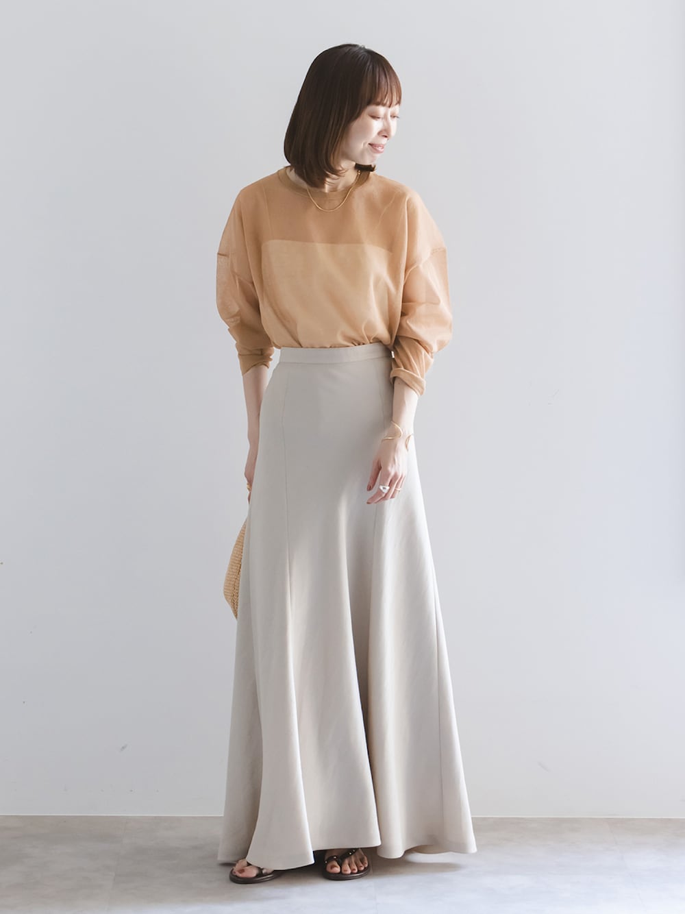 イエロー系のニット/セーター、ホワイト系のキャミソール、ベージュ系のスカートを着用したレディースの春コーディネートの1枚目の写真