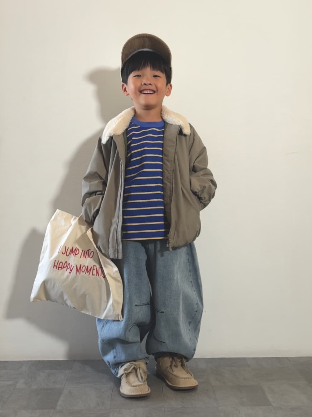 ベージュ系のトートバッグ、ブルー系のTシャツ/カットソー、ベージュ系のモカシン/デッキシューズを着用したキッズの秋コーディネートの1枚目の写真
