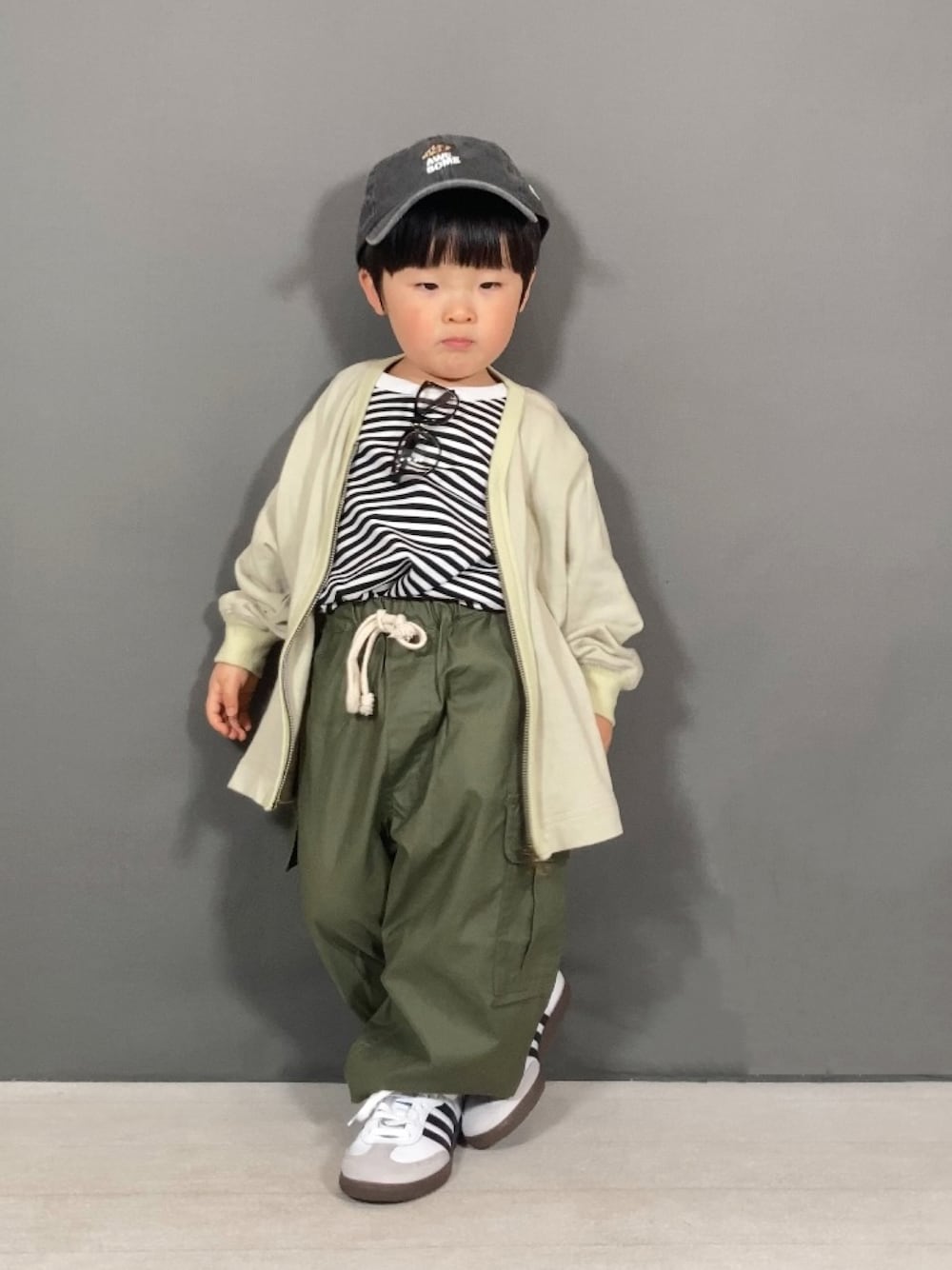 ベージュ系のカーディガン/ボレロ、ホワイト系のTシャツ/カットソー、グリーン系のカーゴパンツを着用したキッズの春コーディネートの1枚目の写真