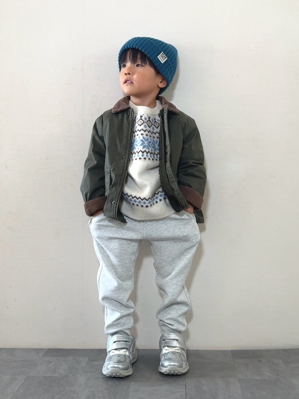 シルバー系のスニーカー、ホワイト系のニット/セーター、グリーン系のジャケット/アウターを着用したキッズの秋コーディネートの1枚目の写真