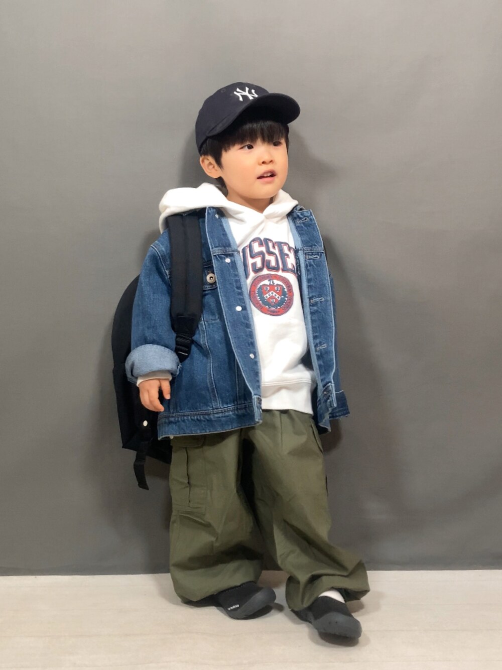 ブルー系のデニムジャケット、ホワイト系のスウェット、グリーン系のカーゴパンツを着用したキッズの冬コーディネートの1枚目の写真