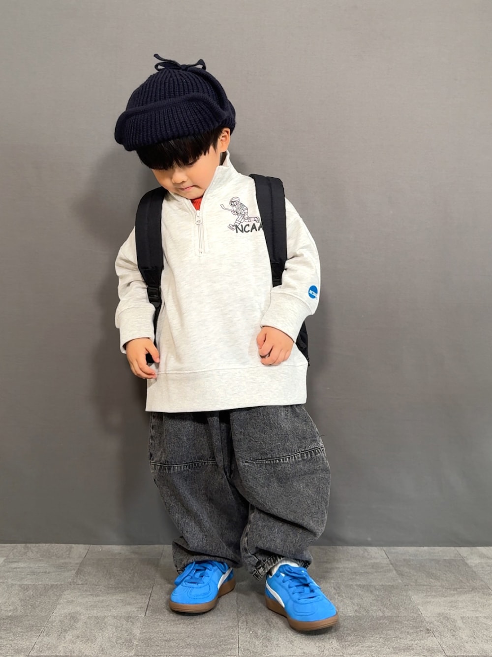 グレー系のスウェット、オレンジ系のTシャツ/カットソー、ブラック系のデニムパンツを着用したキッズの冬コーディネートの1枚目の写真