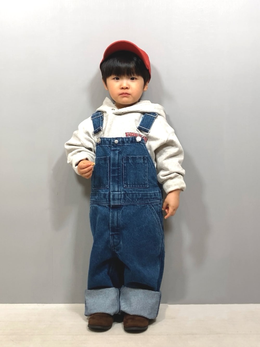 グレー系のスウェット、ブルー系のサロペット/オーバーオール、ブラウン系のブーツを着用したキッズの冬コーディネートの1枚目の写真