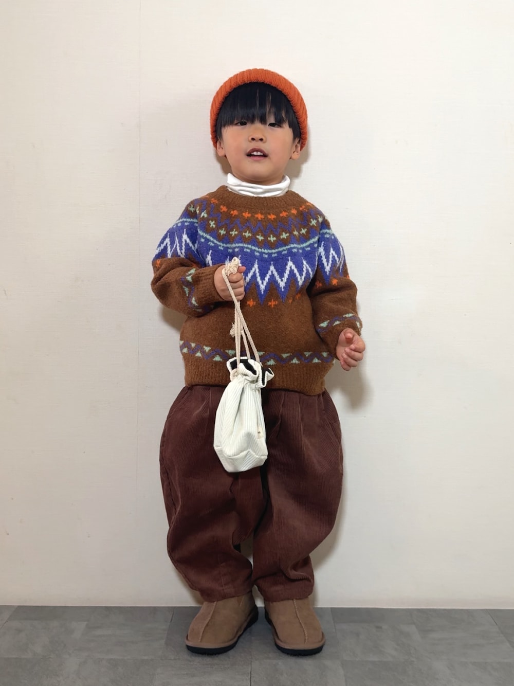 イエロー系のブーツ、ブラウン系のニット/セーター、ブラウン系のその他パンツを着用したキッズの冬コーディネートの1枚目の写真