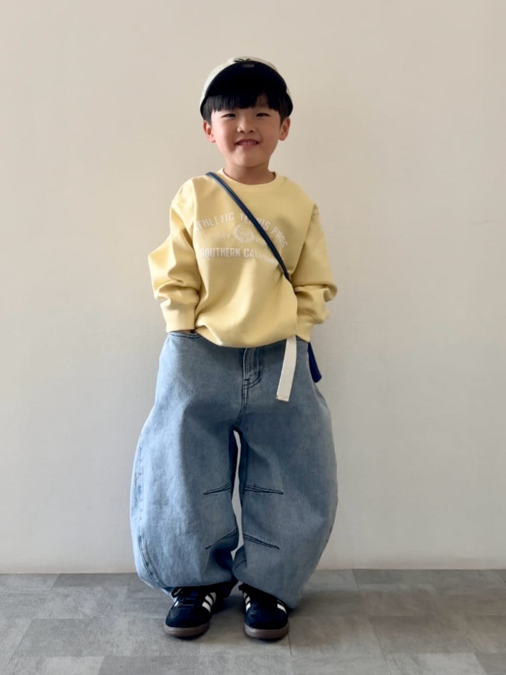 ブラック系のスニーカー、ブルー系のデニムパンツ、ブルー系のショルダーバッグを着用したキッズの春コーディネートの1枚目の写真