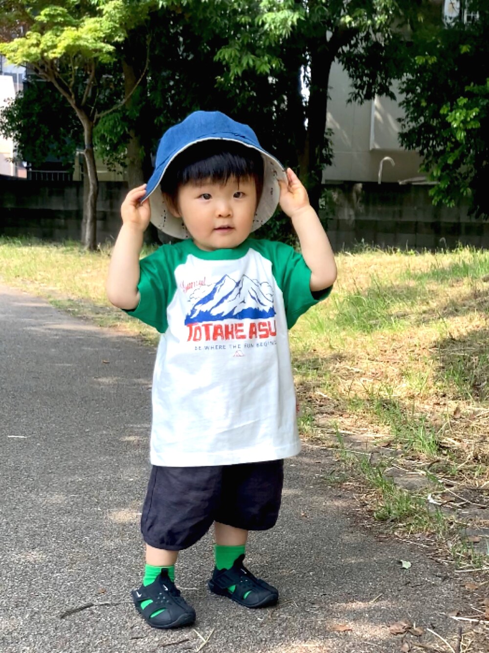 グリーン系のTシャツ/カットソー、ブラック系のパンツ、ブラック系のサンダルを着用したキッズの春コーディネートの1枚目の写真