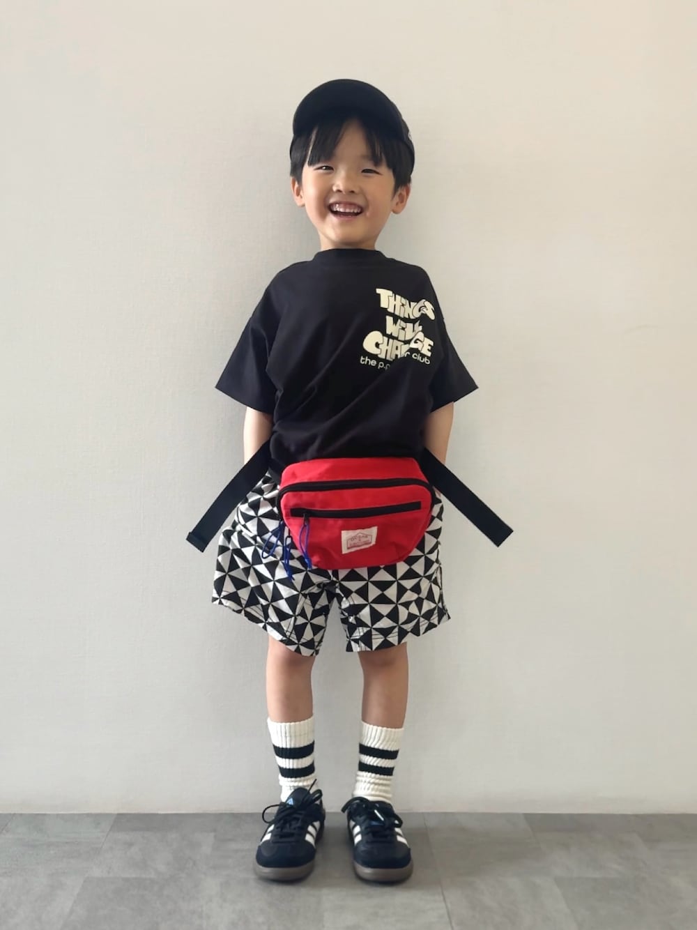 ブラック系のスニーカー、ブラック系のTシャツ/カットソー、レッド系のボディバッグ/ウエストポーチを着用したキッズの春コーディネートの1枚目の写真