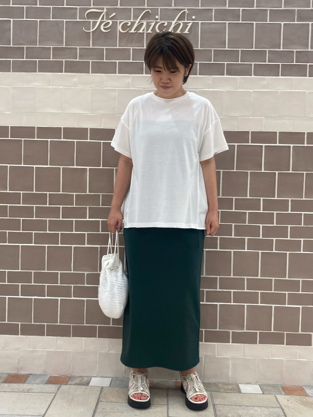 ホワイト系のTシャツ/カットソー、グリーン系のスカート、ホワイト系のハンドバッグを着用したレディースの夏コーディネートの1枚目の写真