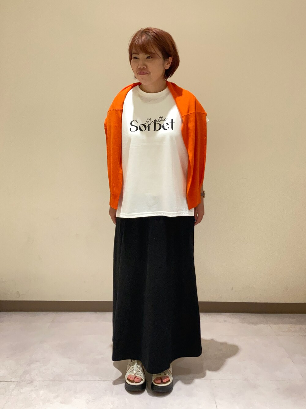 ホワイト系のTシャツ/カットソー、ブラック系のスカート、オレンジ系のカーディガン/ボレロを着用したレディースの夏コーディネートの1枚目の写真